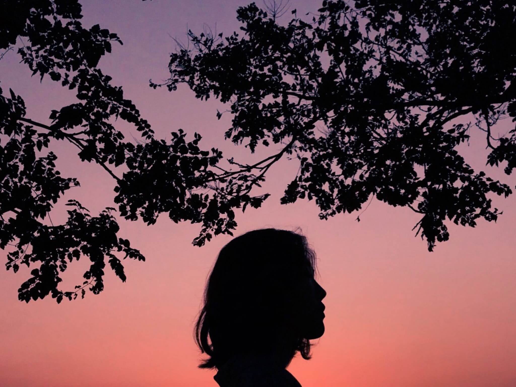 Sunset view with silhouette of woman and trees
